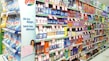 A supermarket aisle filled with various cleaning products, organized neatly on shelves. Promotional sale tags are visible on many items, indicating discounted prices. A promotional stand-up banner on the left features a smiling woman holding clean laundry, with a slogan in Hindi.