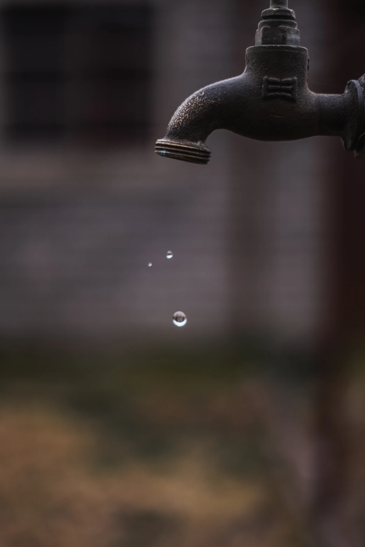Water droplets falling from a running faucet against a dark backdrop