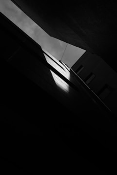 Black and white photo capturing a quiet alley bathed in soft morning light.