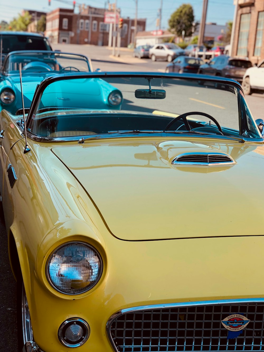 two vintage convertible coupes at the side of the street