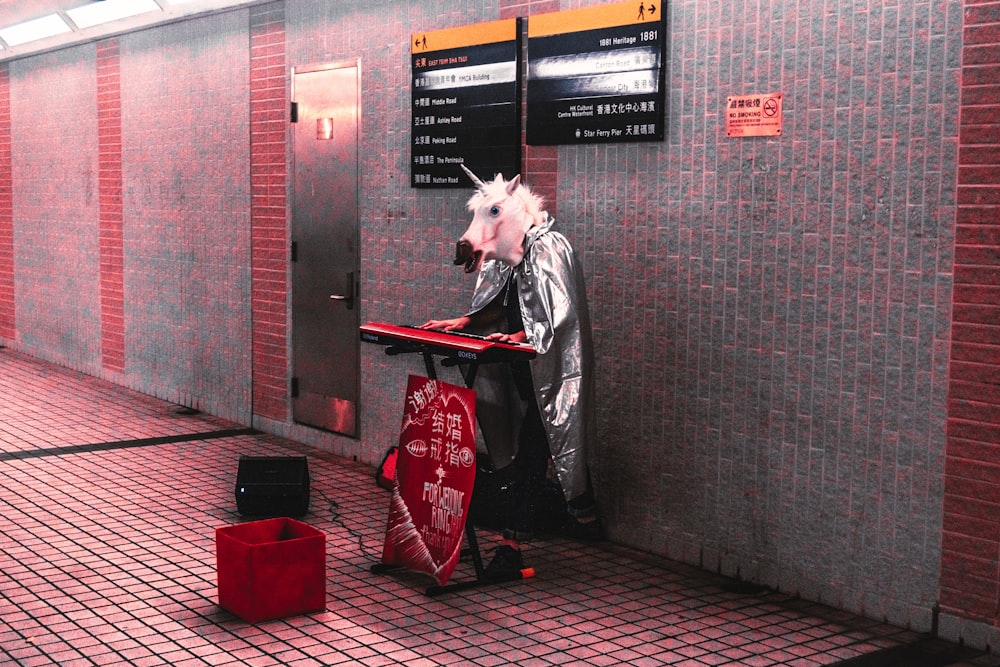 Person mit Einhornkopf und Umhang spielt Keyboard am Bahnhof