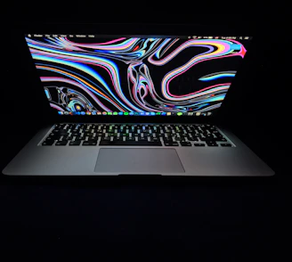 A vibrant laptop covered with colorful Kerala-themed stickers on a dark green background.