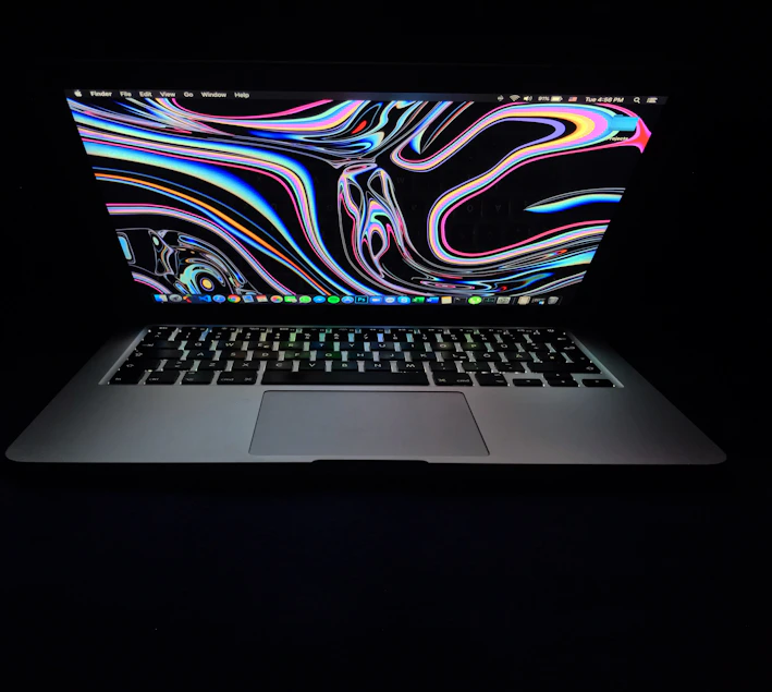A vibrant laptop covered with colorful Kerala-themed stickers on a dark green background.