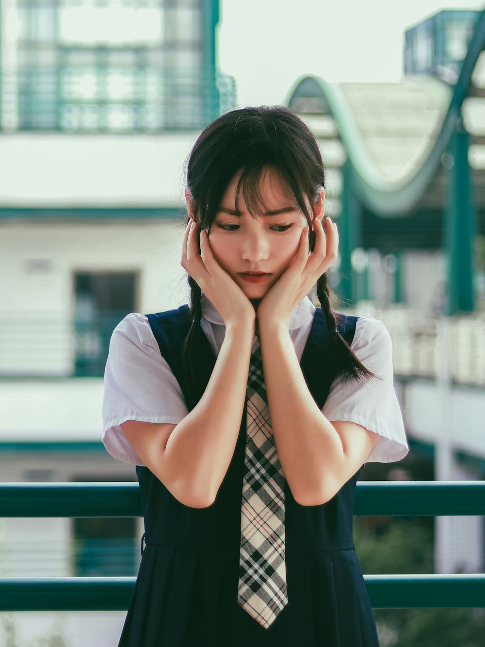 woman holding her face standing near white and green concrete building