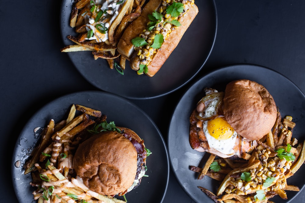 three sandwiches on black plates