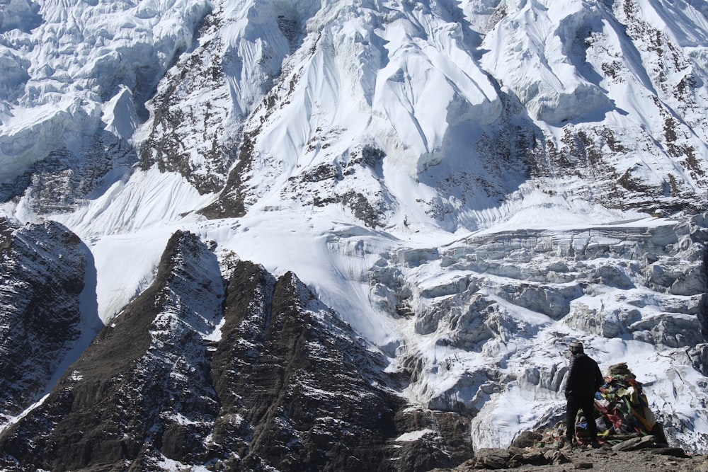 person standing beside white and black high mountain during daytime
