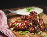 A close-up of crispy golden chicken wings glazed with spicy sauce, steaming hot on a rustic plate.