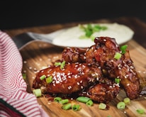 A vibrant plate of chicken wings glazed in spicy sauce, surrounded by fresh dipping sauces.