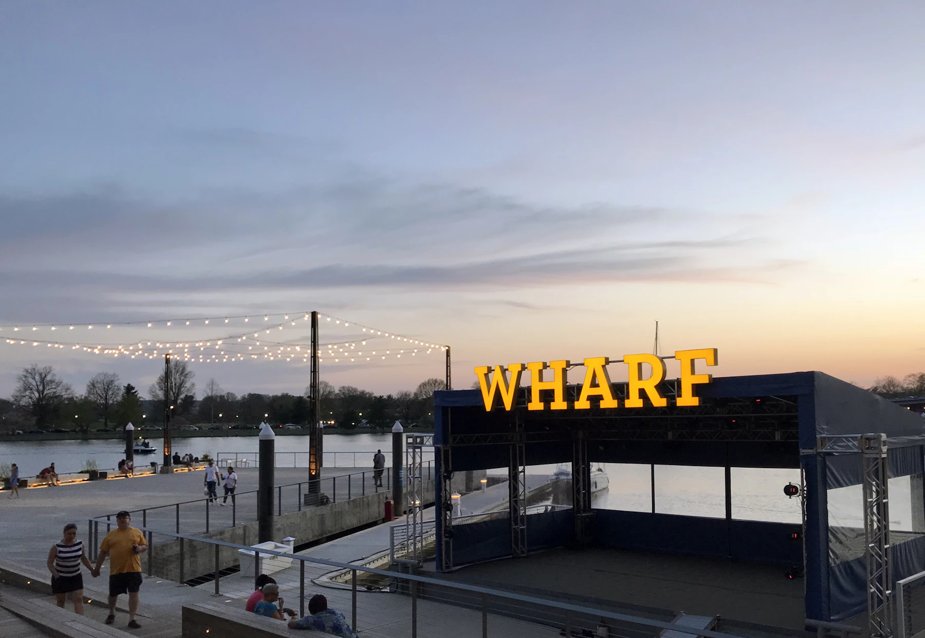 People relaxing beside the water at The Wharf at sunset