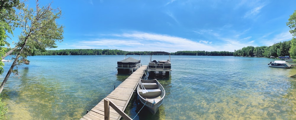 white and gray canoe beside gray wooden dock surrounded by body of water at daytime