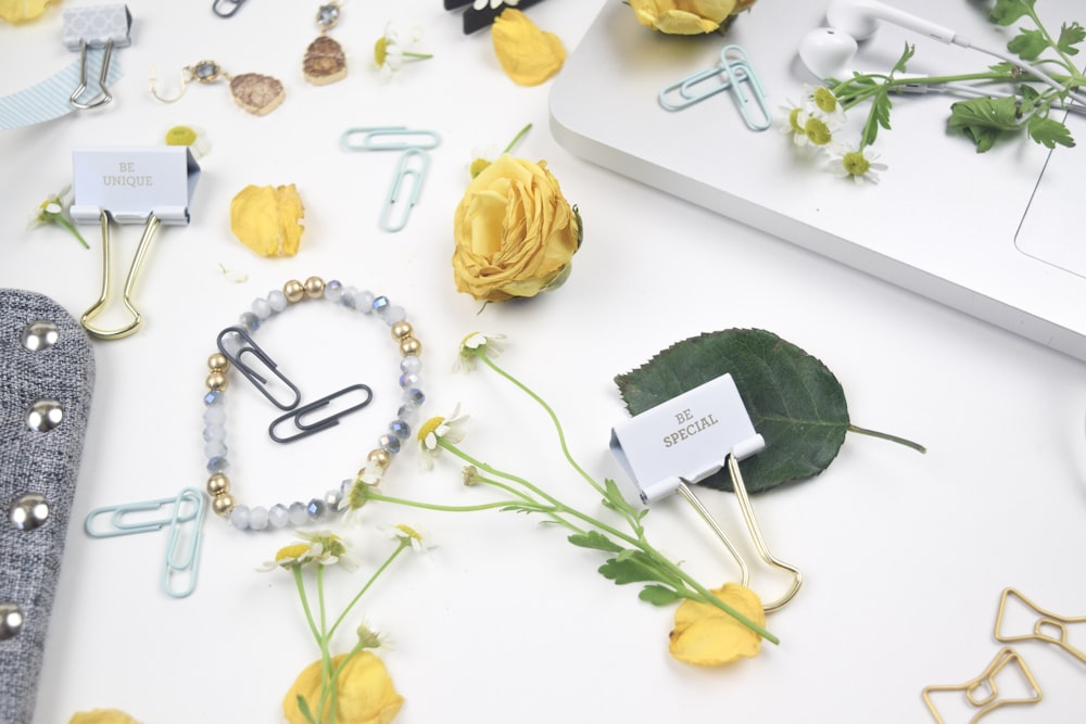 flatlay photo of flowers, paper clips, and bracelet