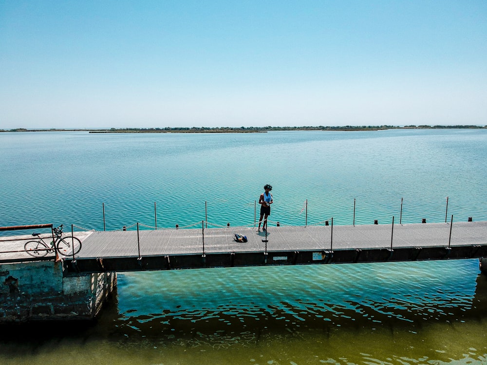 man standing on a bridge above sea