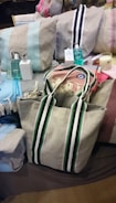 A variety of fabric bags with different colored stripes are arranged alongside toiletries, such as perfume bottles and soap. There is also a decorative evil eye charm and a candle.