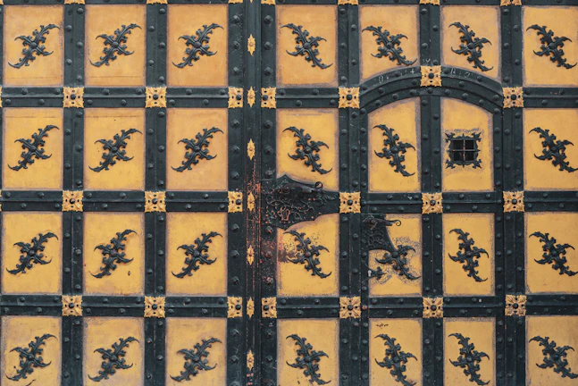 Close-up of a sturdy black forged iron door with intricate scrollwork.