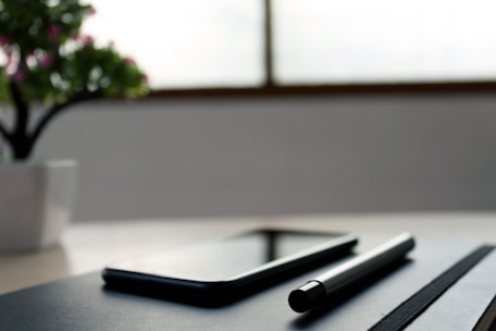Close-up of a notebook and pen beside a smartphone playing a therapeutic audio track.