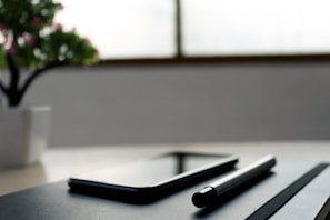 A vibrant notebook and pen set next to a smartphone on a wooden table, bathed in natural light