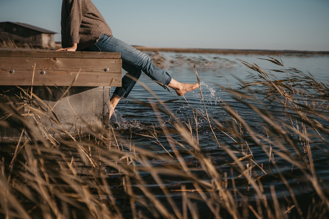 man playing with water while sitting on wooden dock