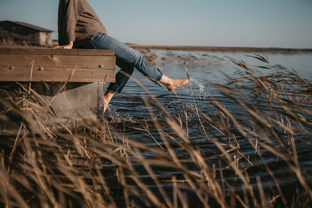 man playing with water while sitting on wooden dock