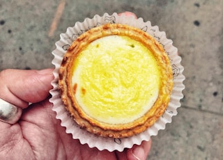 person holding round brown cupcake