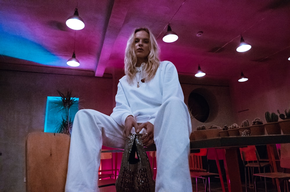 woman wearing white long-sleeved shirt and pants sitting on chair