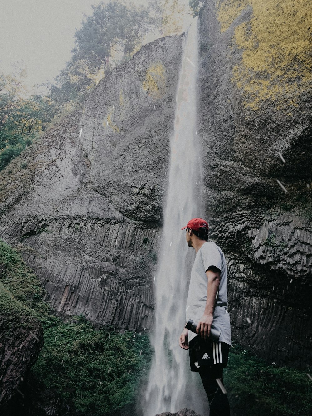 man standing beside waterfall