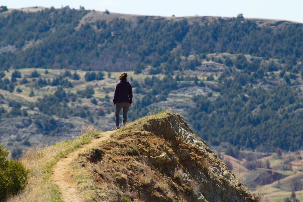 man standing at the clip of mountain ]