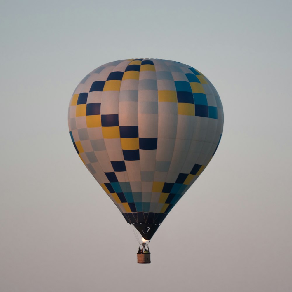 Globo aerostático azul, blanco y amarillo en vuelo