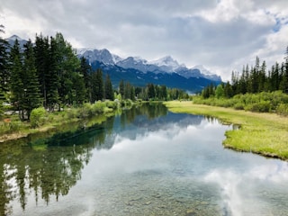 Cinematic 4k image of a snow-capped mountain reflected in a crystal-clear blue river.