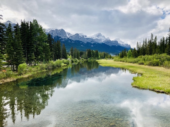 A cinematic 4k image of a crystal-clear blue river winding through snow-capped mountains under a twilight sky.