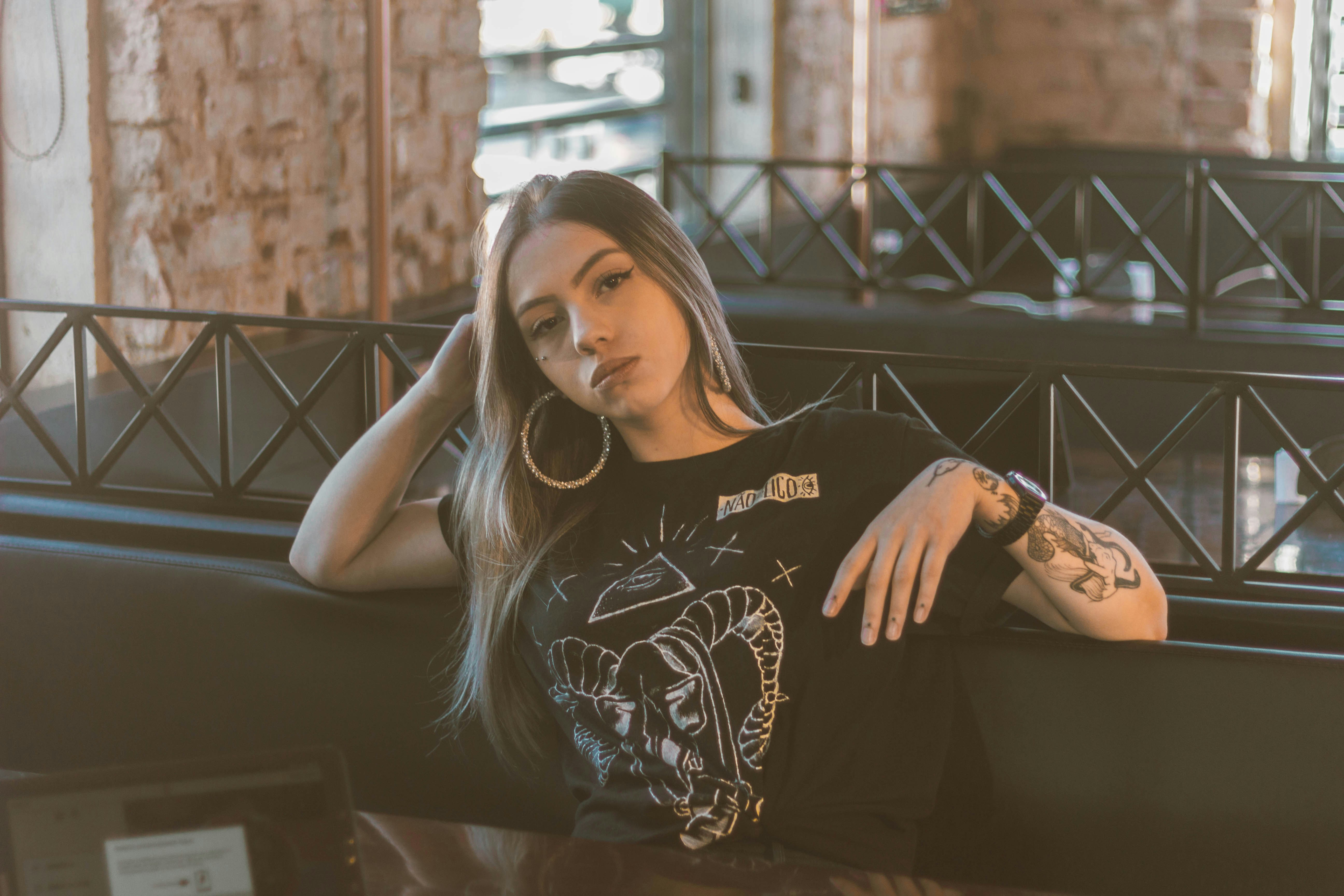 검은 셔츠를 입은 여자가 벤치에 앉아서 기대고 있습니다.