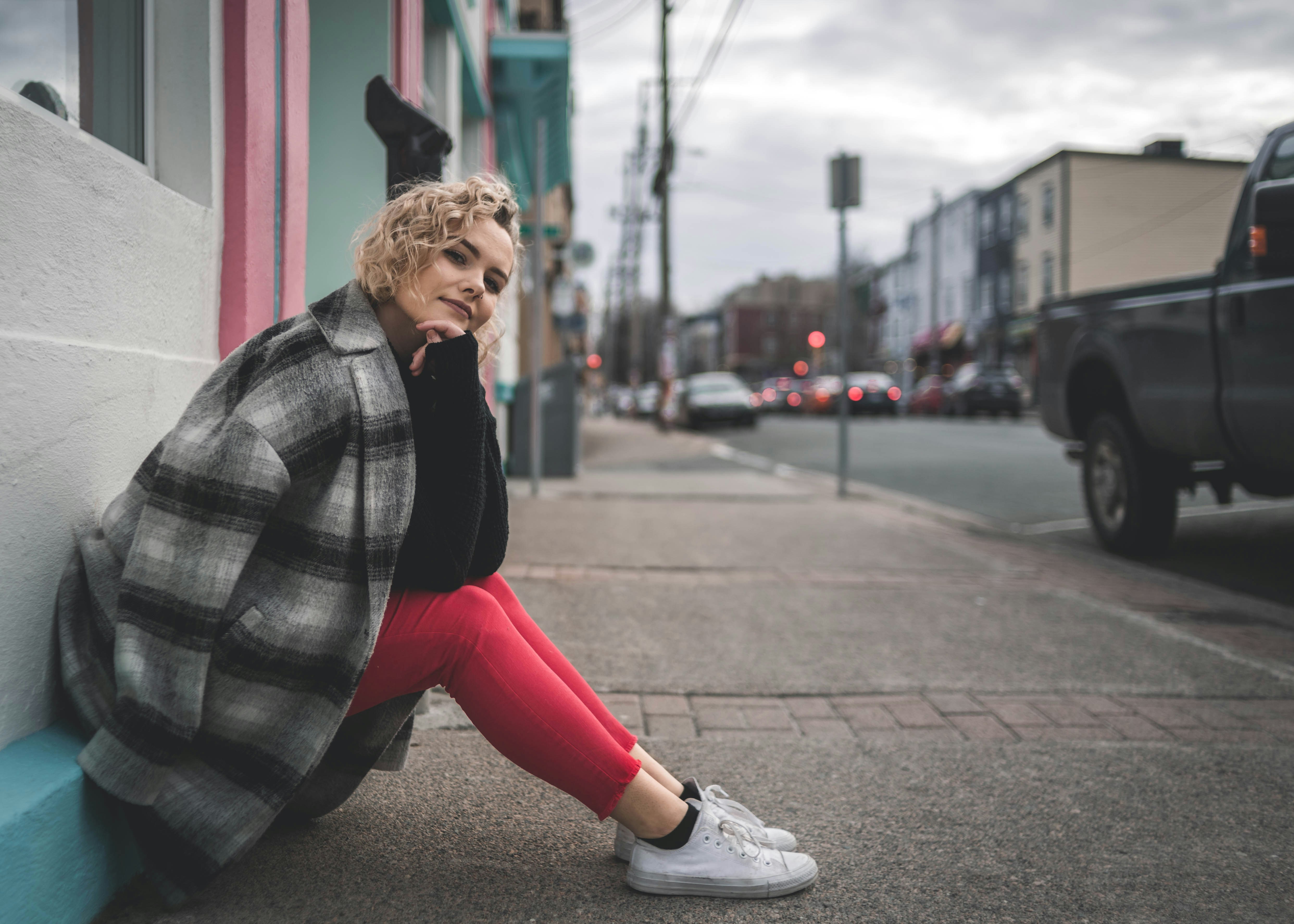 woman sitting on sidewalk during daytime