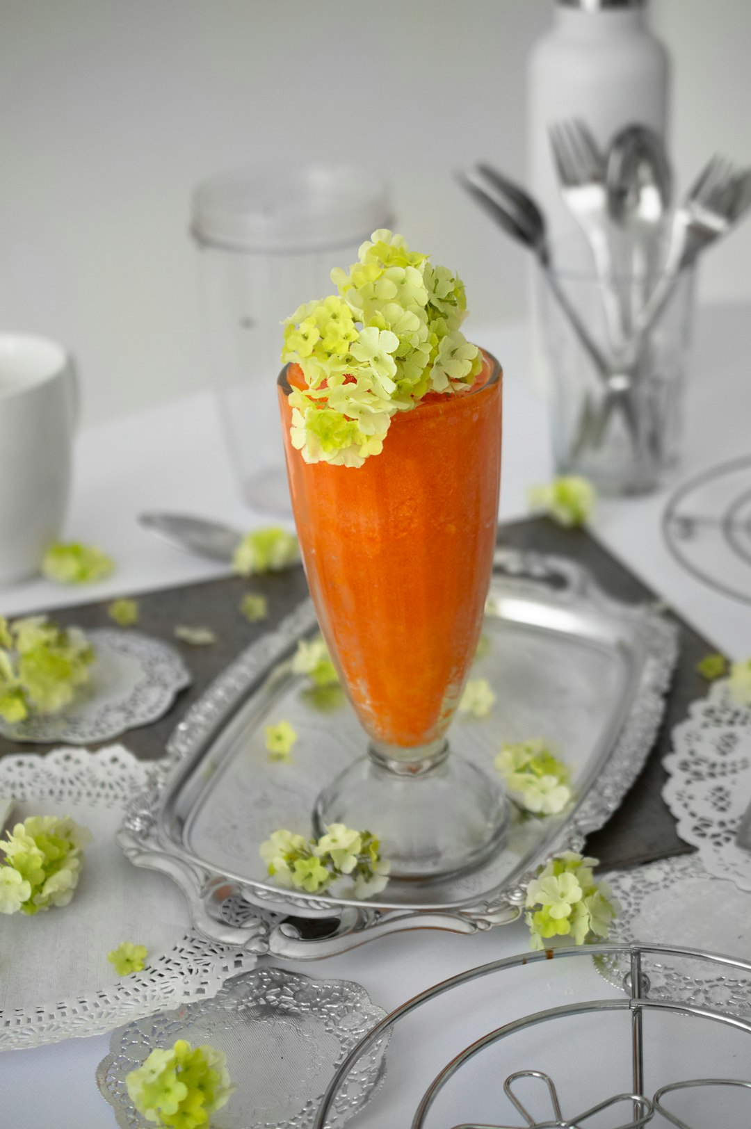 orange shake in footed drinking glass with petaled flowers