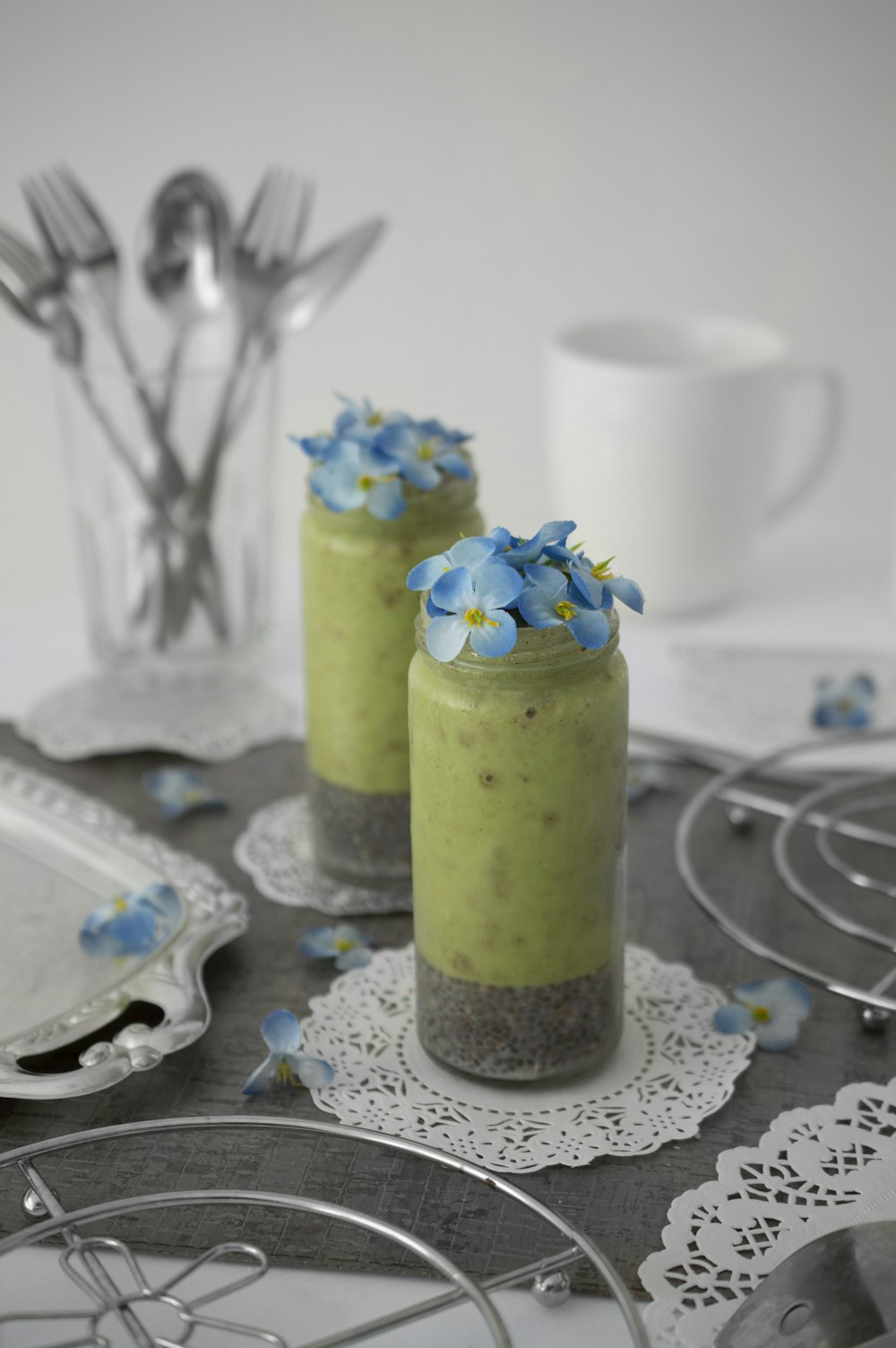 blue petaled flower in glass on table beside plates