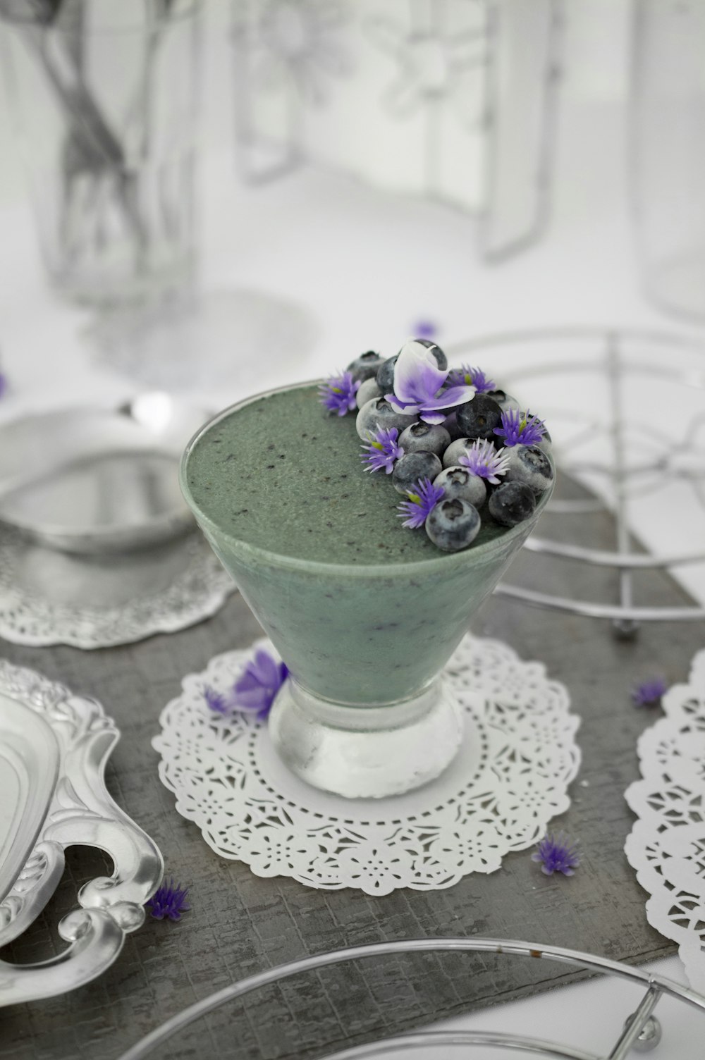 blueberries and purple-petaled flowers on top on clear glass cup