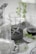 A collection of clear plastic blender containers and a blade attachment are arranged on a surface with decorative silverware and green plant sprigs scattered around. The scene includes doily-like placements, creating a mix of industrial and natural elements.