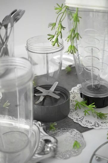 A sleek Kadena blender on a kitchen counter surrounded by fresh fruits and vegetables.