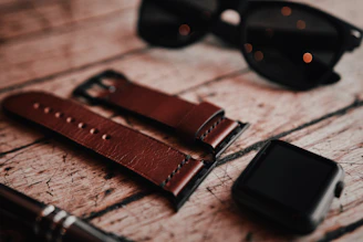 A sleek black and gold watch paired with stylish sunglasses resting on a wooden table.