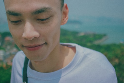 A close-up portrait of a person smiling naturally in an outdoor setting.