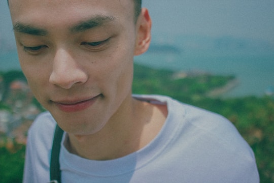 A close-up portrait of a person smiling naturally against a softly blurred outdoor background.
