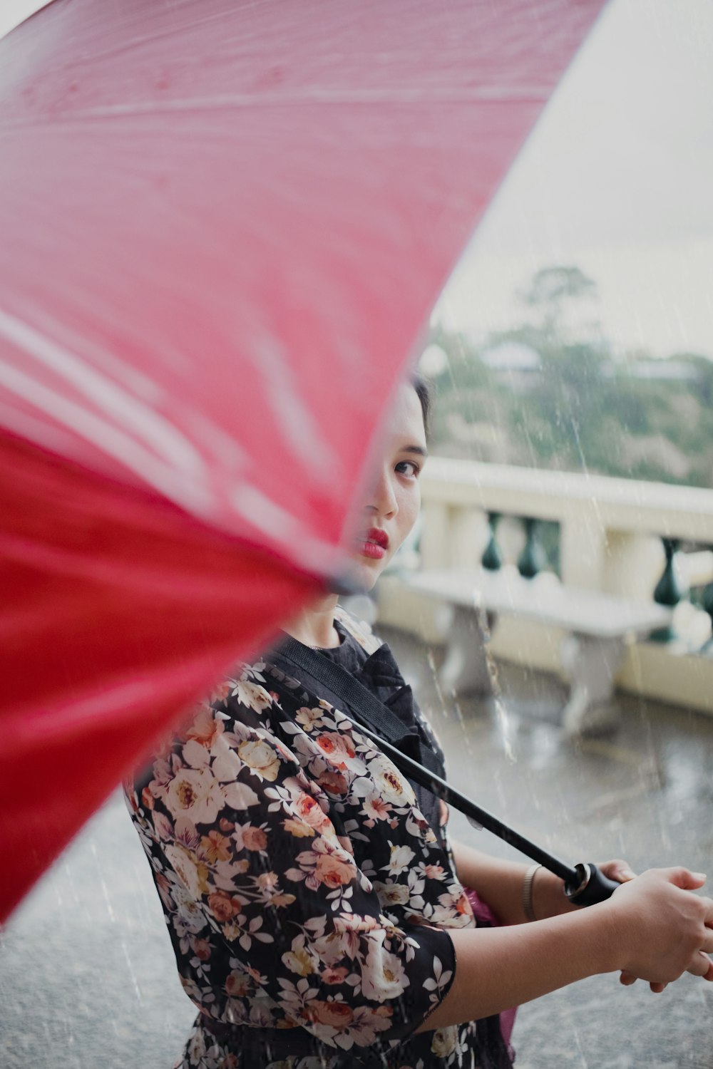 Mujer con top floral bajo paraguas rojo