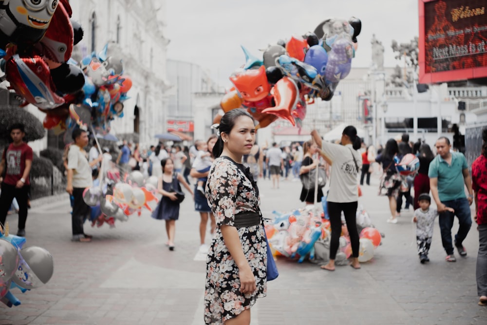 woman wearing multicolored floral dress standing in the middle of road during daytime