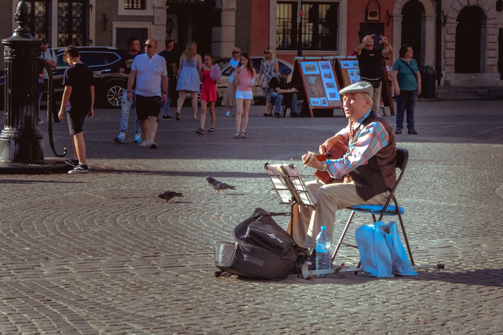 Homme assis sur une chaise pliante jouant de la guitare photo – Photo  Humain Gratuite sur Unsplash