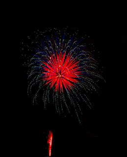 Close-up of striking firework trails painting the dark sky with red, blue, and gold streaks.