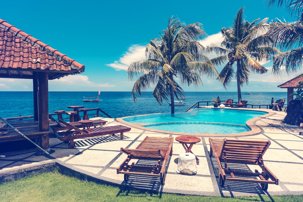 brown wooden outdoor lounger beside pools during daytime