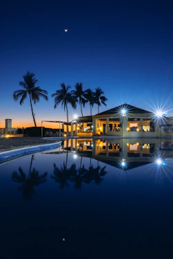 A serene luxury villa at sunset with warm golden lights glowing against a dark sky.