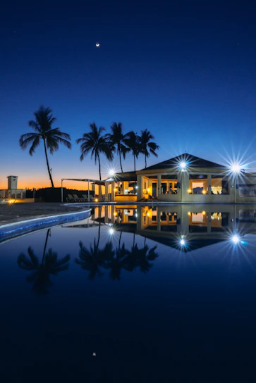 A serene luxury villa at sunset with warm golden lights glowing against a dark sky.