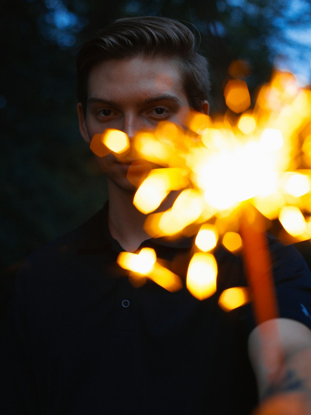 person in black polo shirt holding sparkler