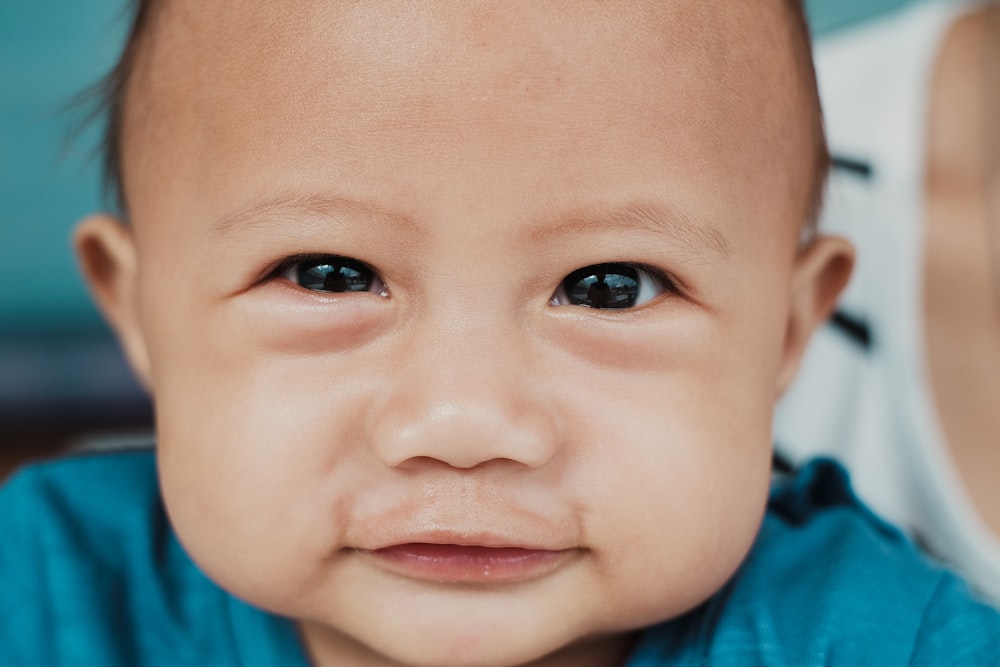 baby wearing blue shirt smiling