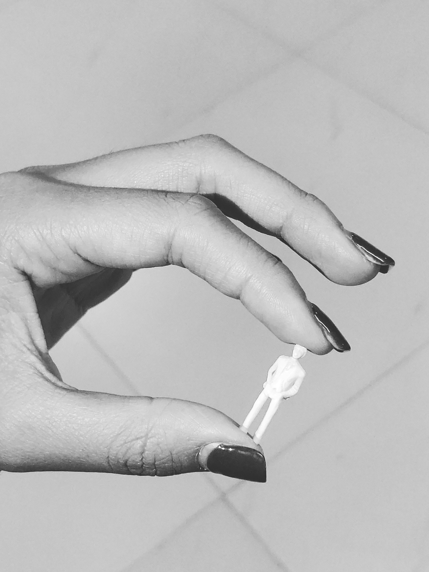 grayscale photography of person holding tiny action figure