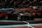A vibrant crowd admiring a sleek exotic car under bright exhibition lights.